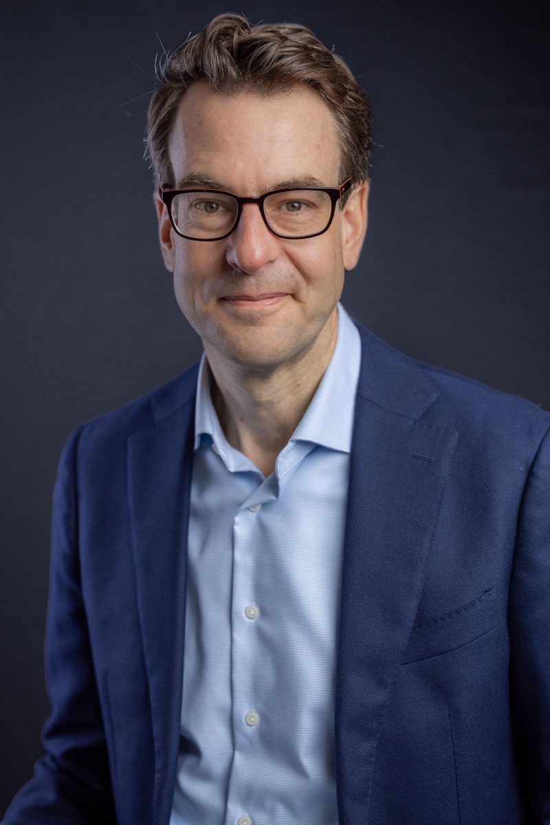 Zakelijk studio-portret man met bril in blauw colbert — portretfotograaf Den Haag