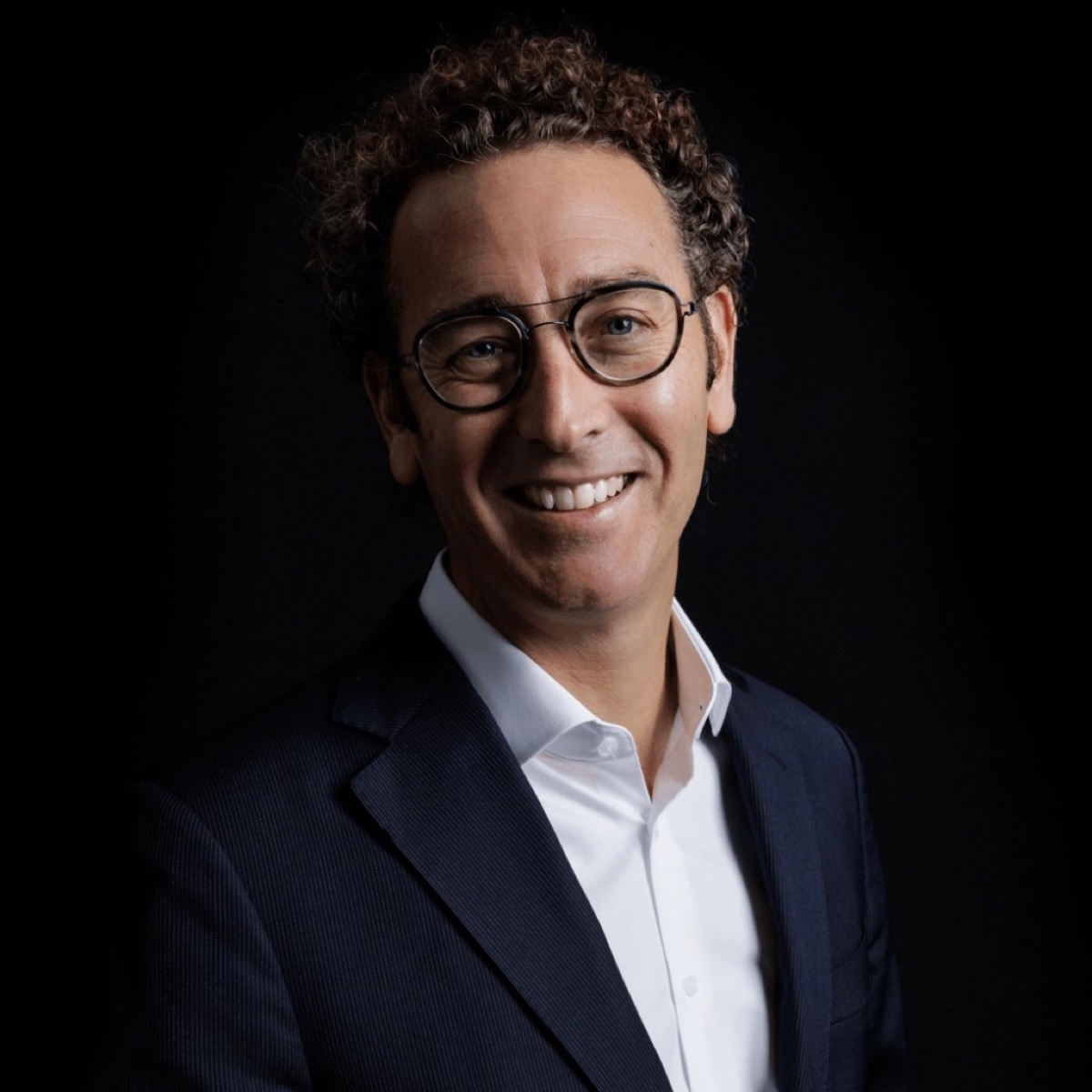 Zakelijk portret man met bril en zwarte achtergrond — LinkedIn profielfoto Den Haag